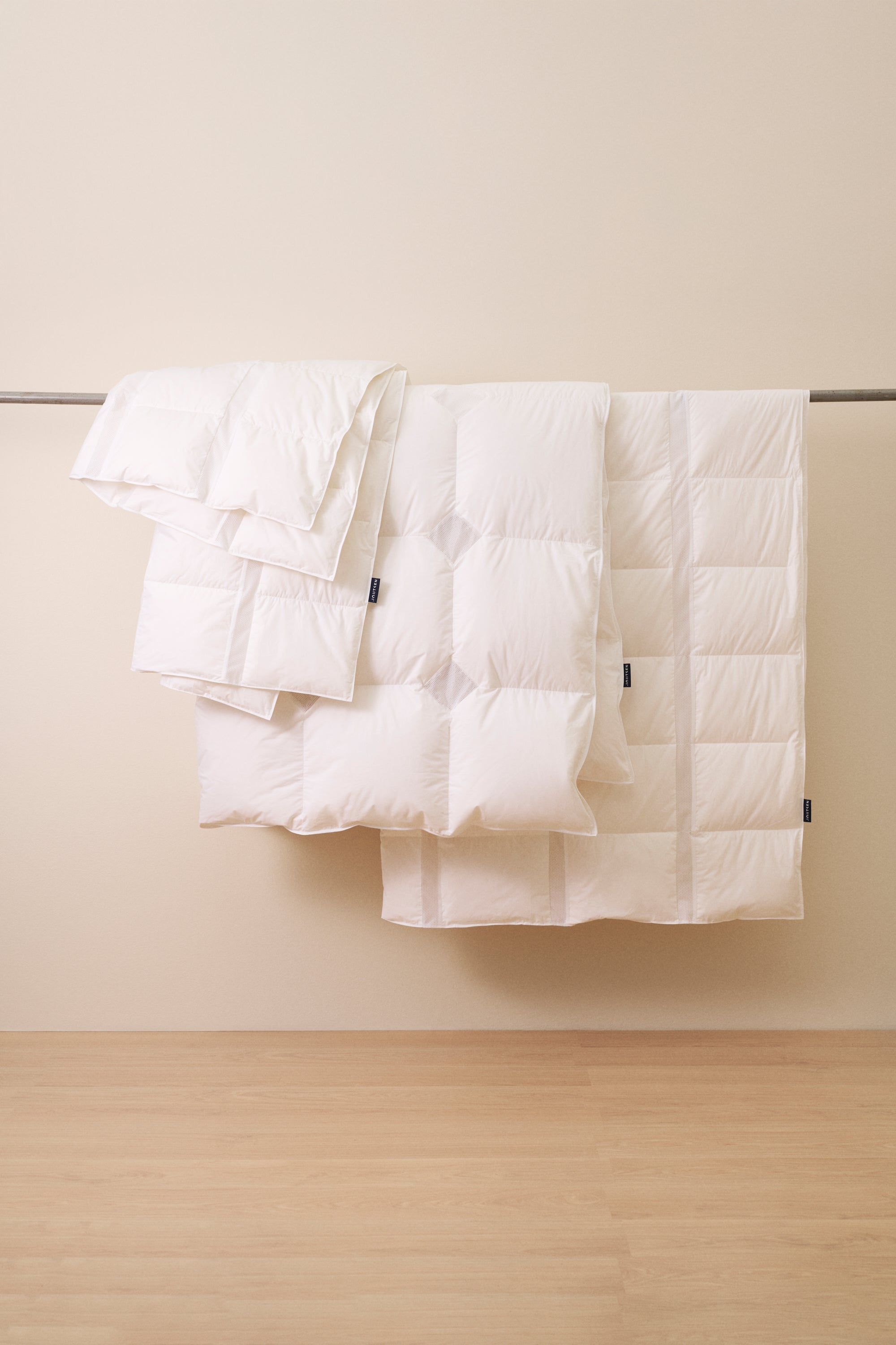 White down duvets on a wooden floor with a neutral wall background