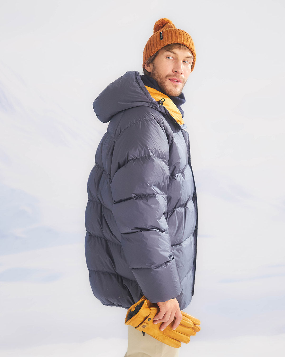 Person wearing a large blue down coat with a white background
