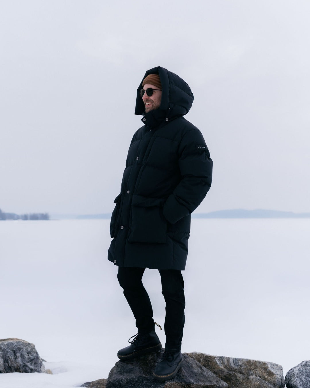 Person wearing a black Tuisku down coat standing on a snowy landscape