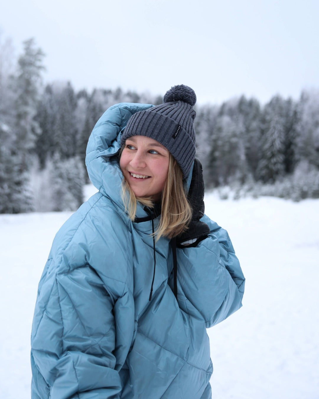 Person wearing a light blue down anorak and gray beanie in a snowy landscape