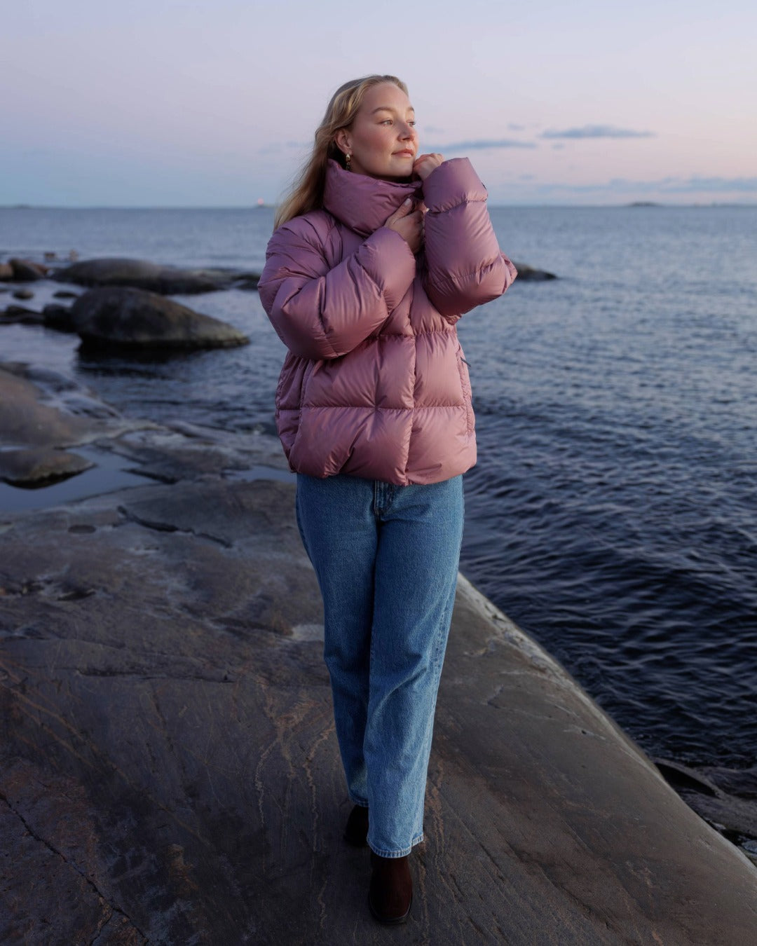 Person wearing a pink puffer jacket standing by the water