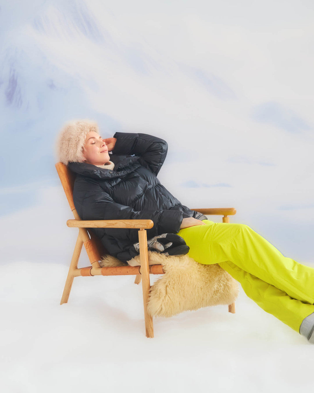 Person sitting in a chair with a fluffy coat against a snowy landscape