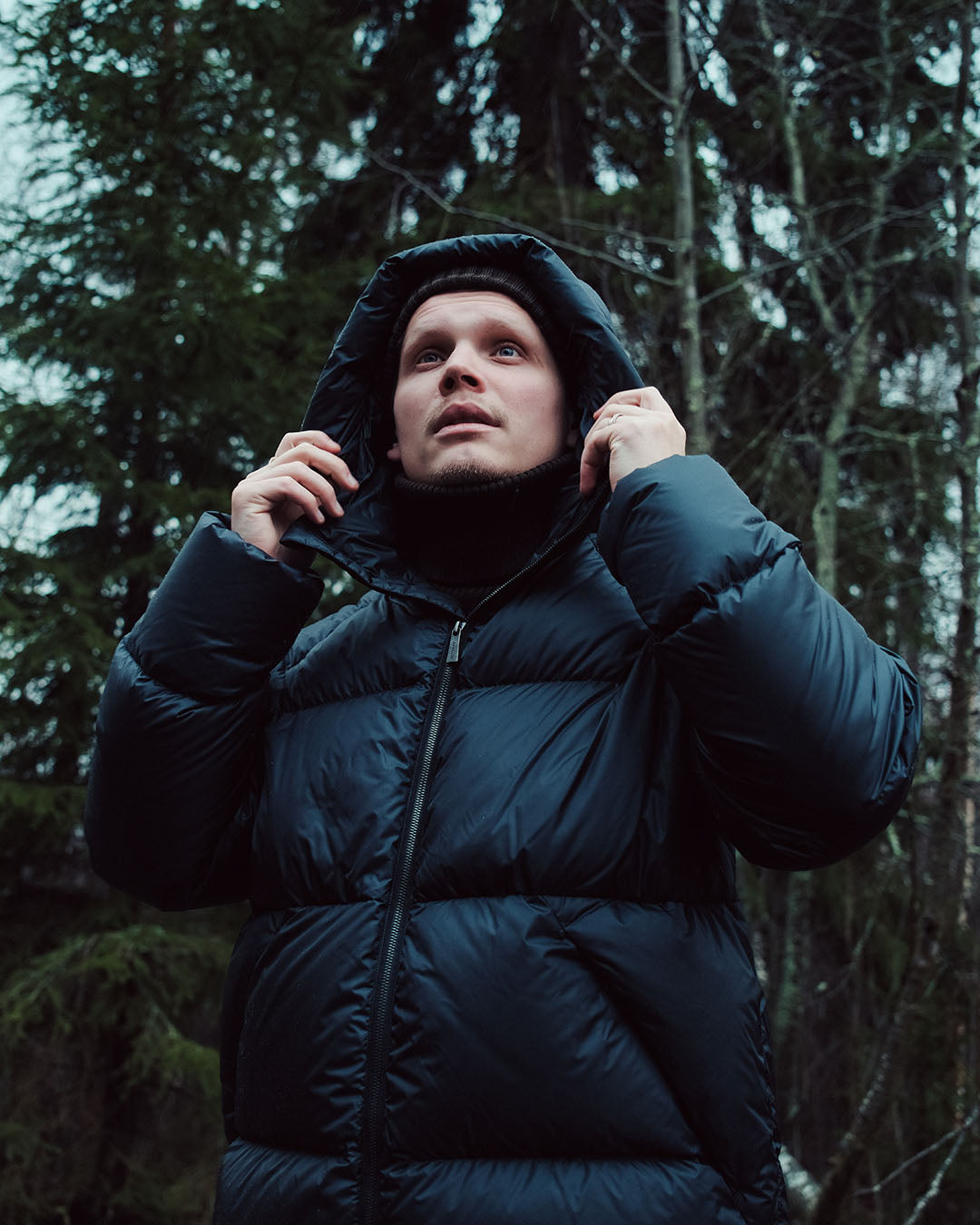 Person wearing a black down coat in a forest setting