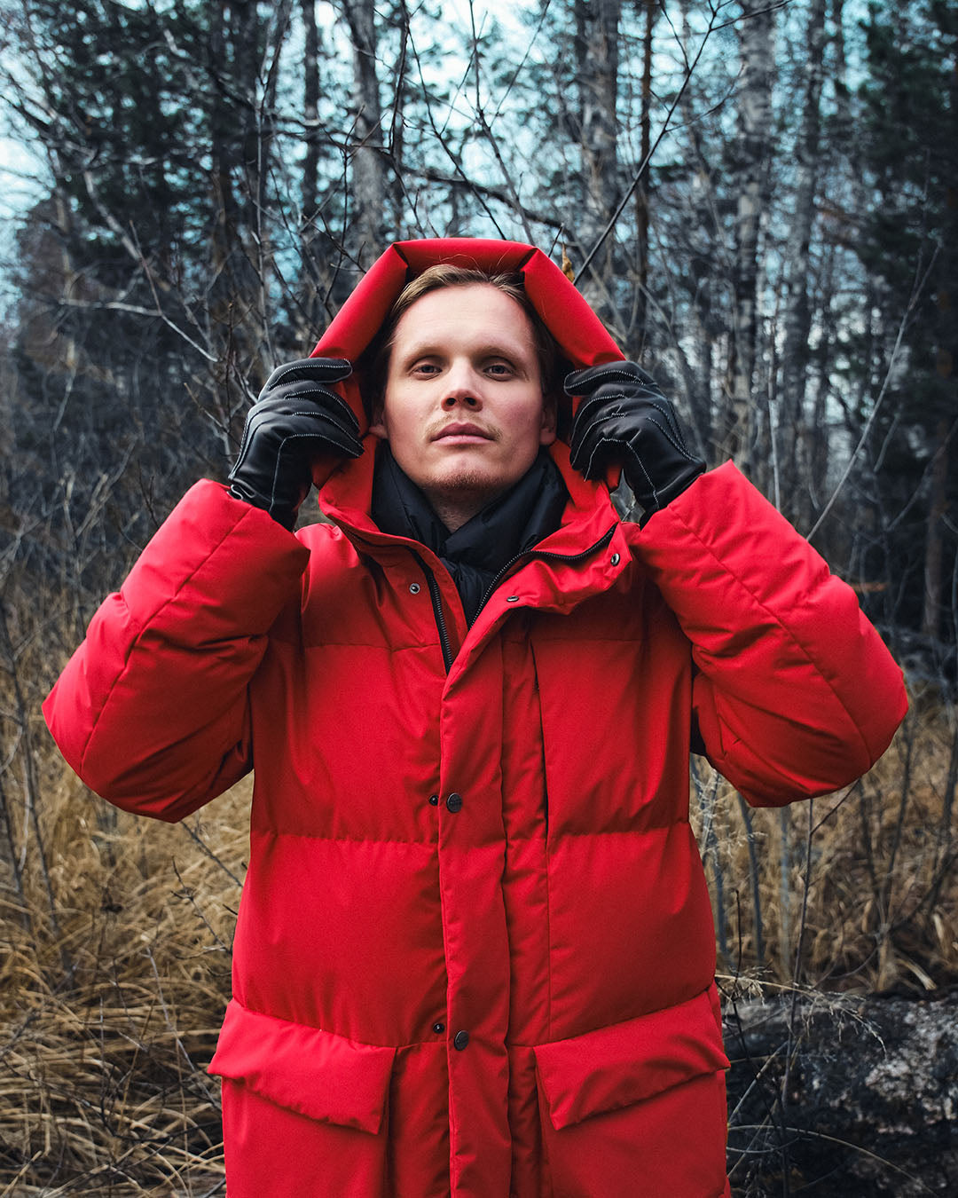 Person wearing a red down coat in a forest setting