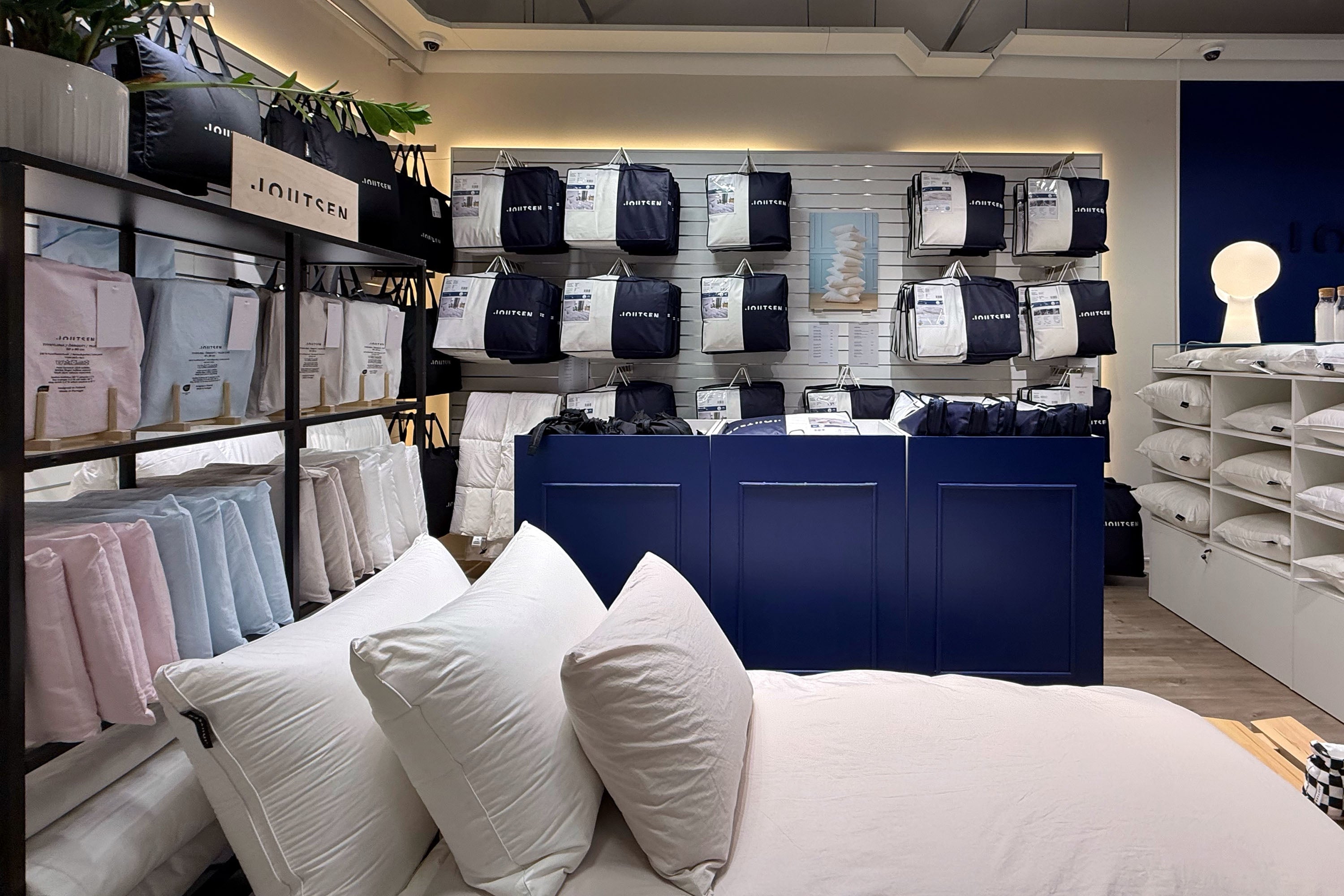 Display of down pillows and bedding in a store with branded packaging.