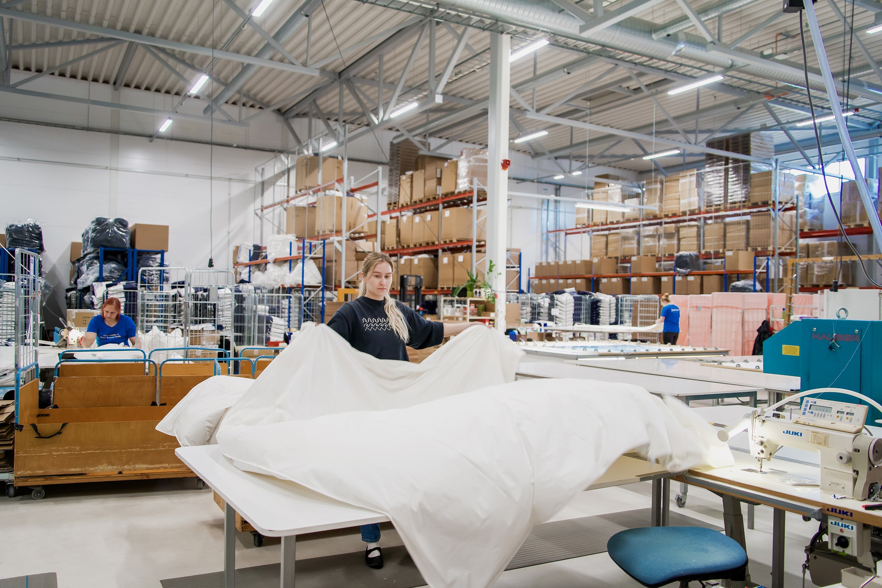 Person working with a white bedding fabric in a warehouse setting