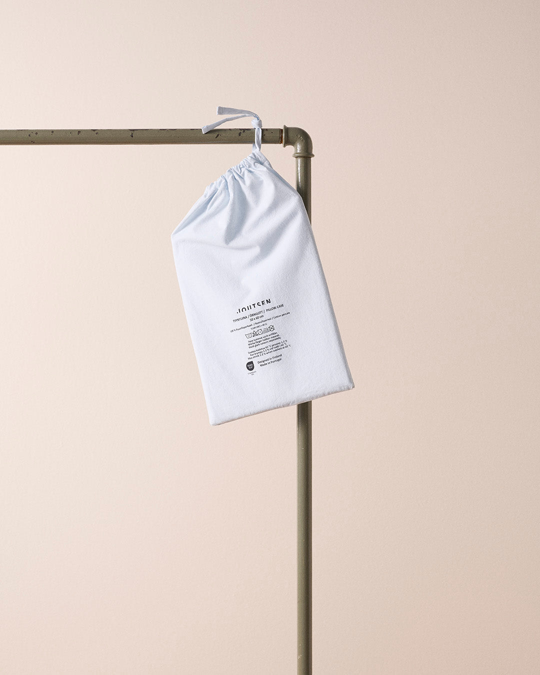 White drawstring bag with text on a metal rod against a beige background