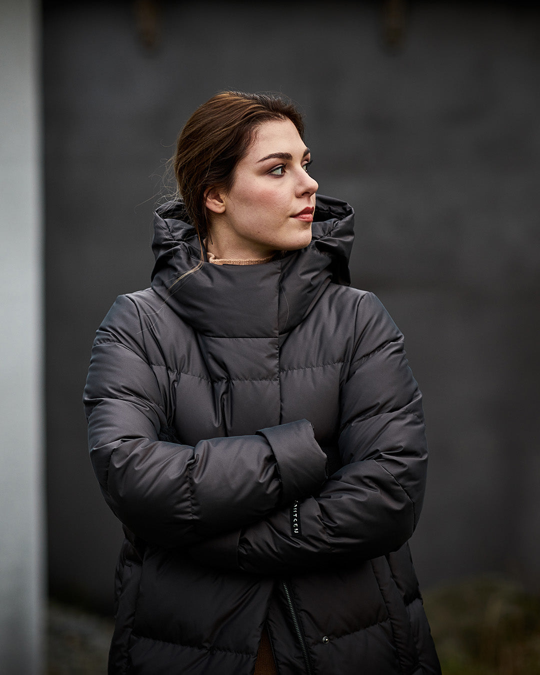 Woman wearing a black puffer coat against a dark background