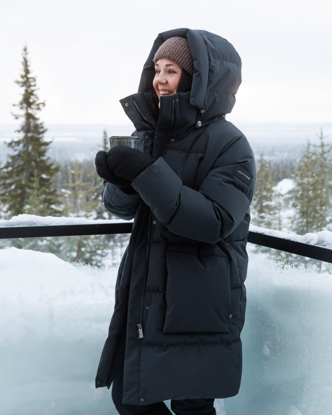 Person wearing a black down coat in a snowy landscape. 