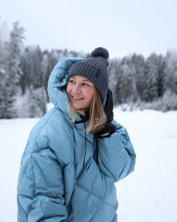 Person wearing a light blue down anorak and gray beanie in a snowy landscape