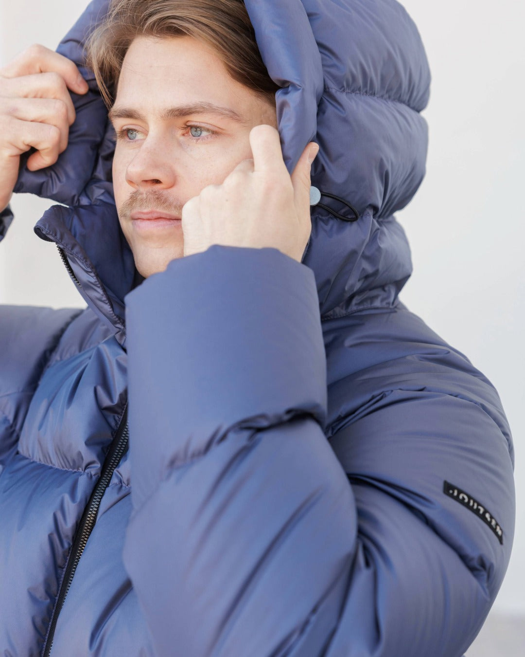 Man wearing a blue Huurre down jacket with a blurred background