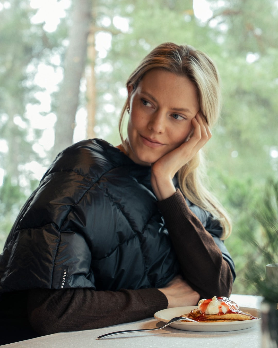 Woman sitting at a table with a plate of food in a forest setting