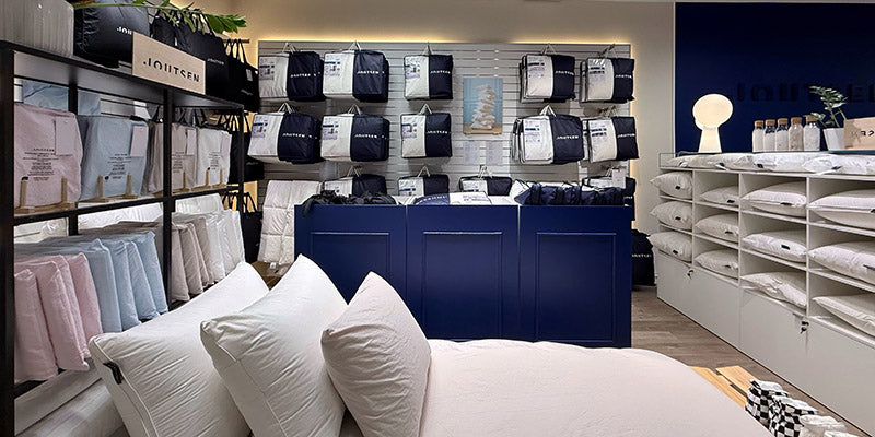 Down bedding store interior with shelves displaying pillows and bedding sets.