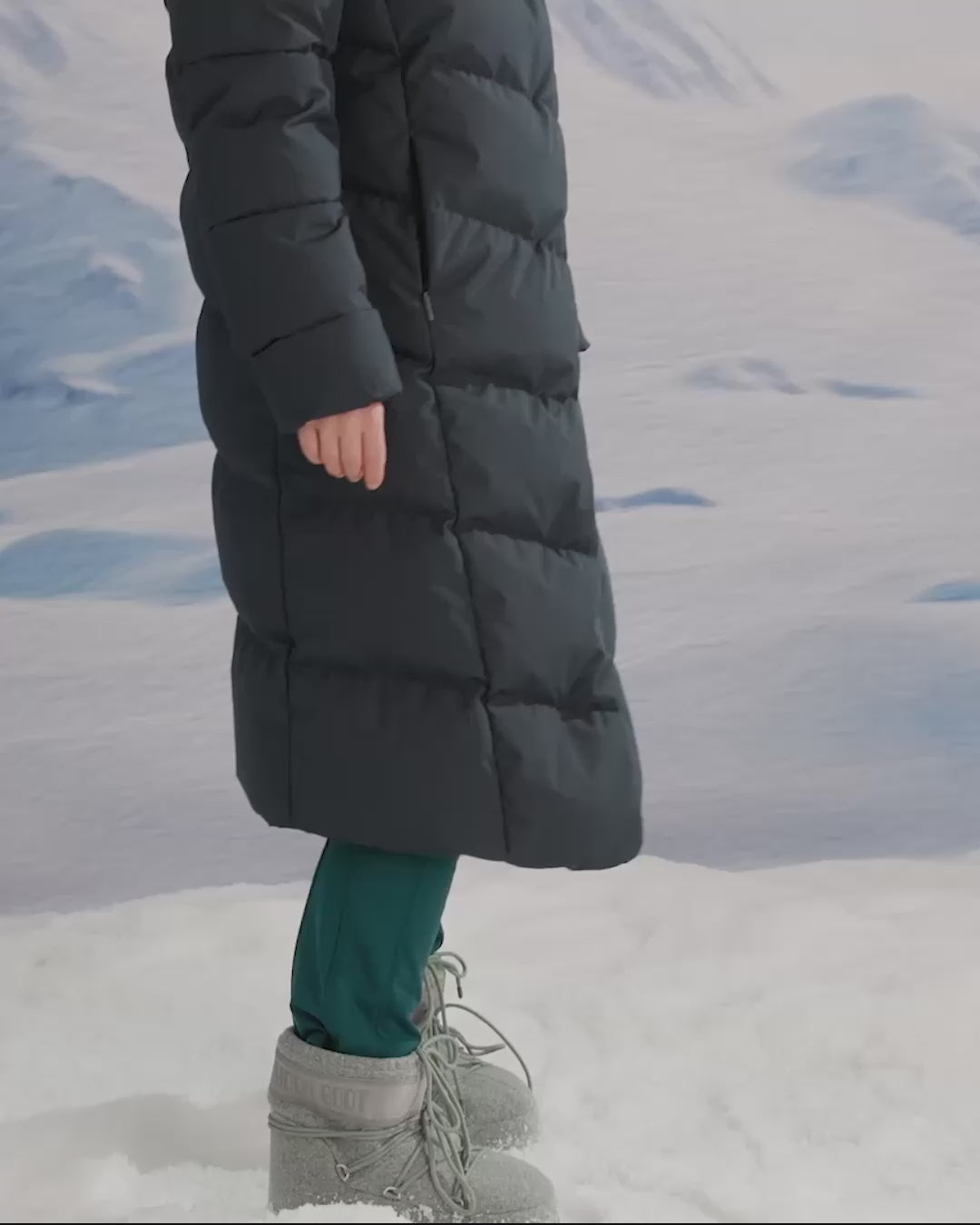 A woman is wearing a long down coat in a snowy scene.
