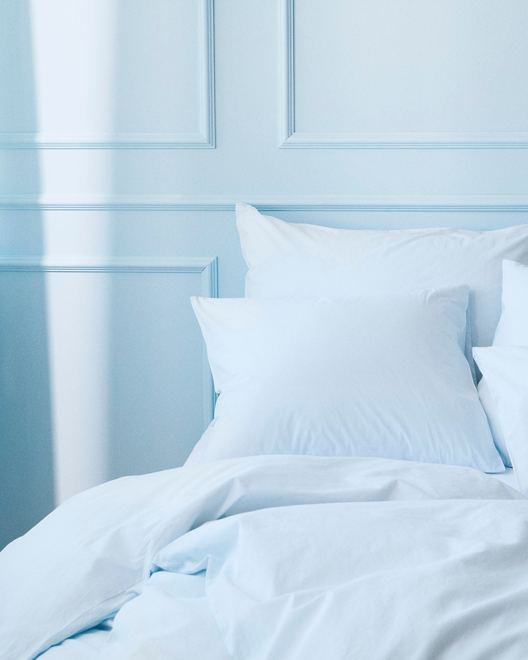 Light blue bedding set on a bed with a matching headboard.