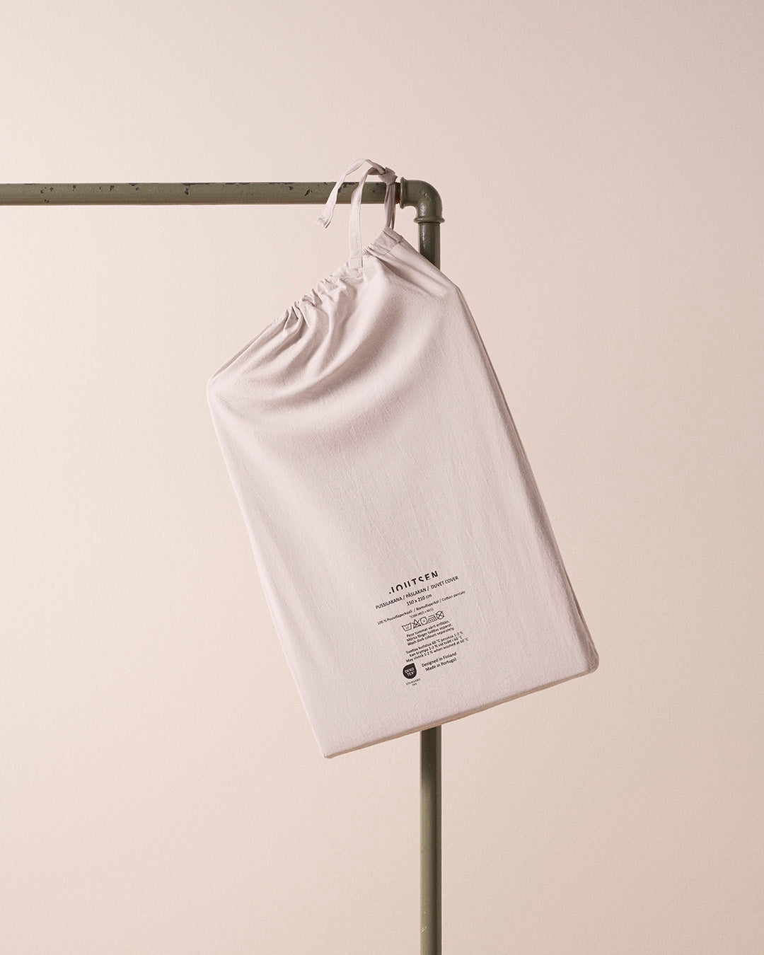 White drawstring bag with text on a metal rack against a beige background