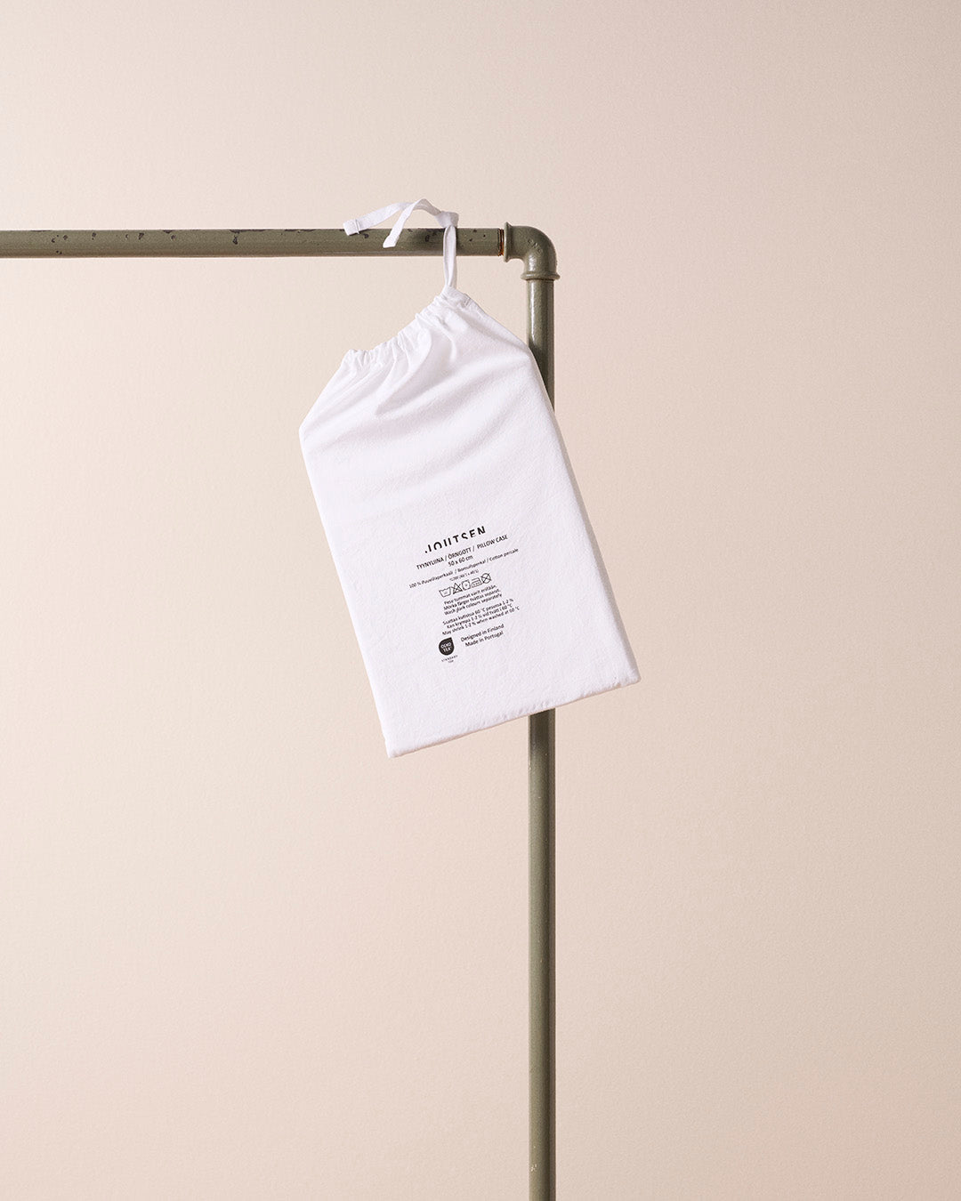 White drawstring bag with text on a metal rack against a beige background