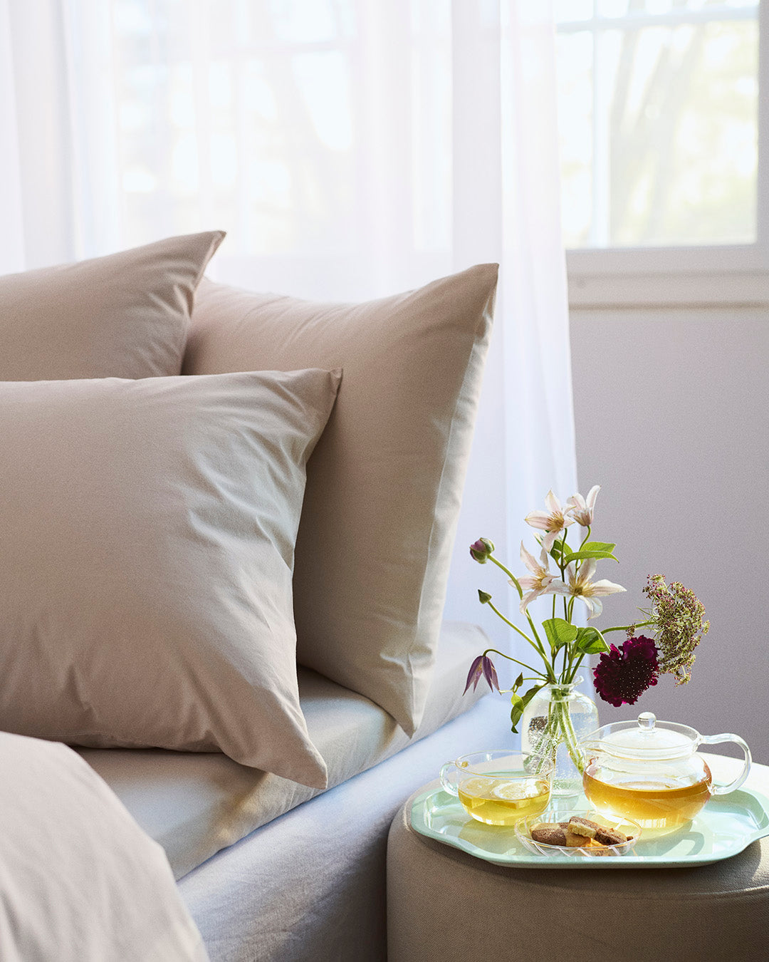 Tea set on a tray with flowers on a sofa