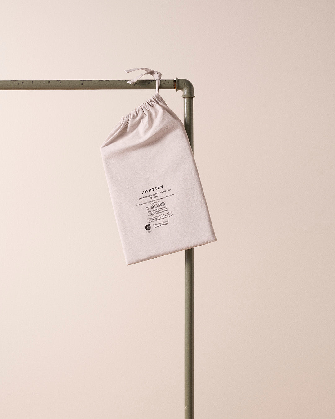 White drawstring bag with text on a metal rack against a beige background